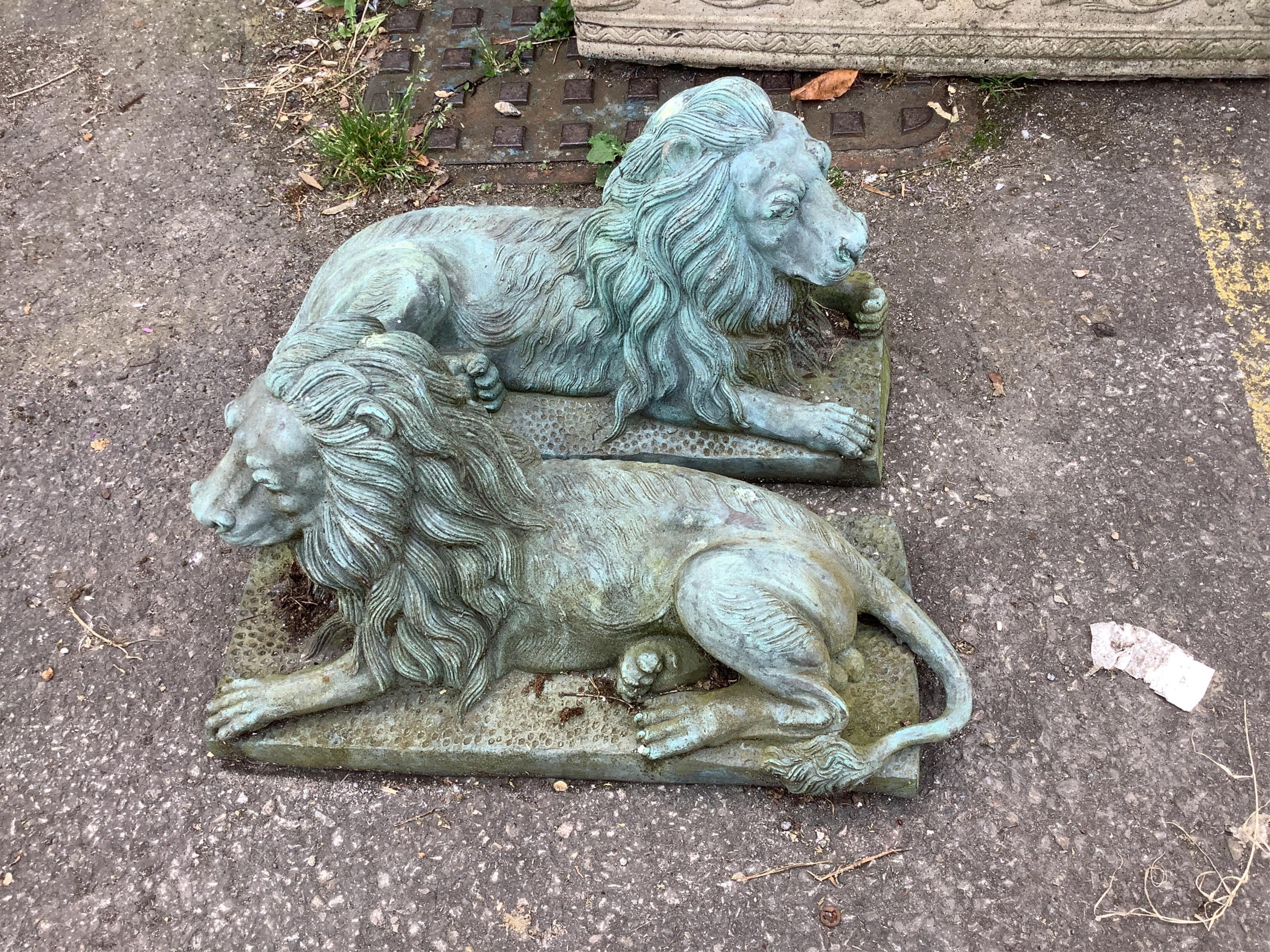 A pair of green patinated cast iron recumbent lions, length 46cm, height 24cm